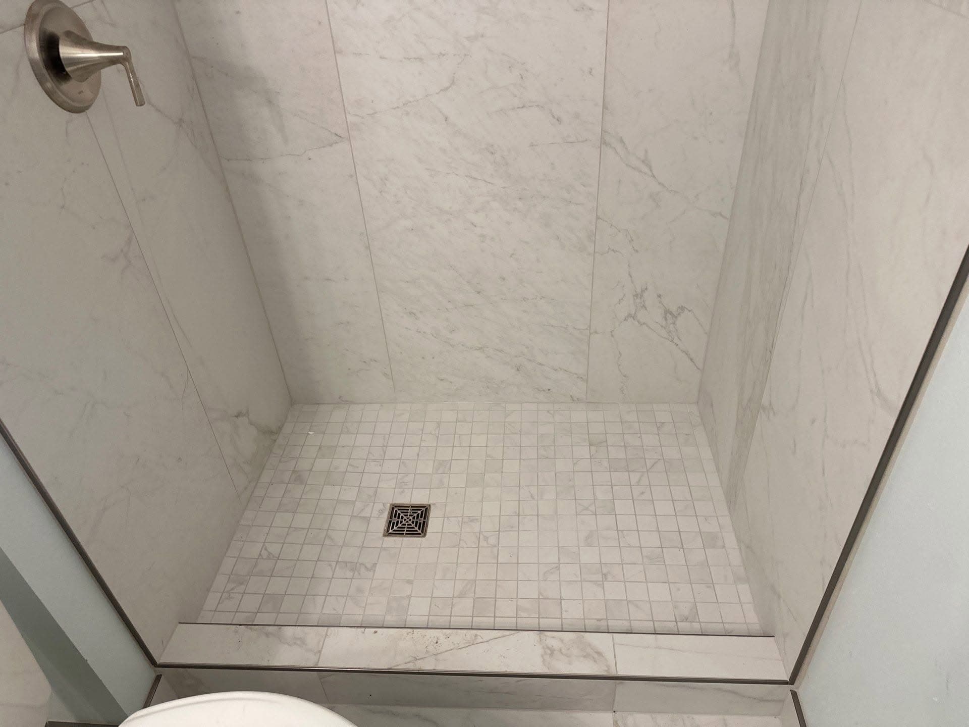 Custom tile shower installation with large-format marble-look walls and a mosaic tile shower pan