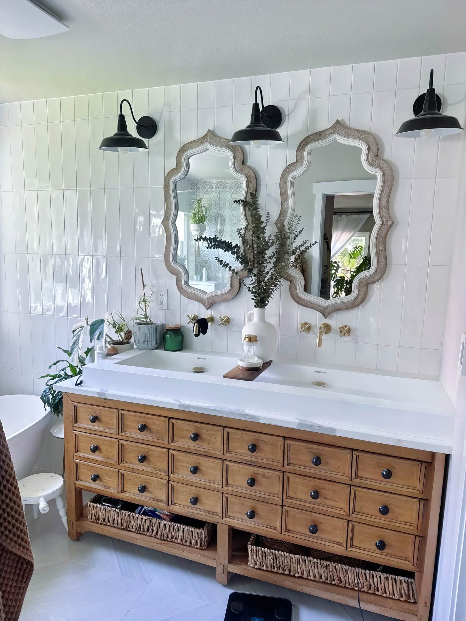Finished tile surround in vertical stacked white tile behind a double vanity and freestanding tub