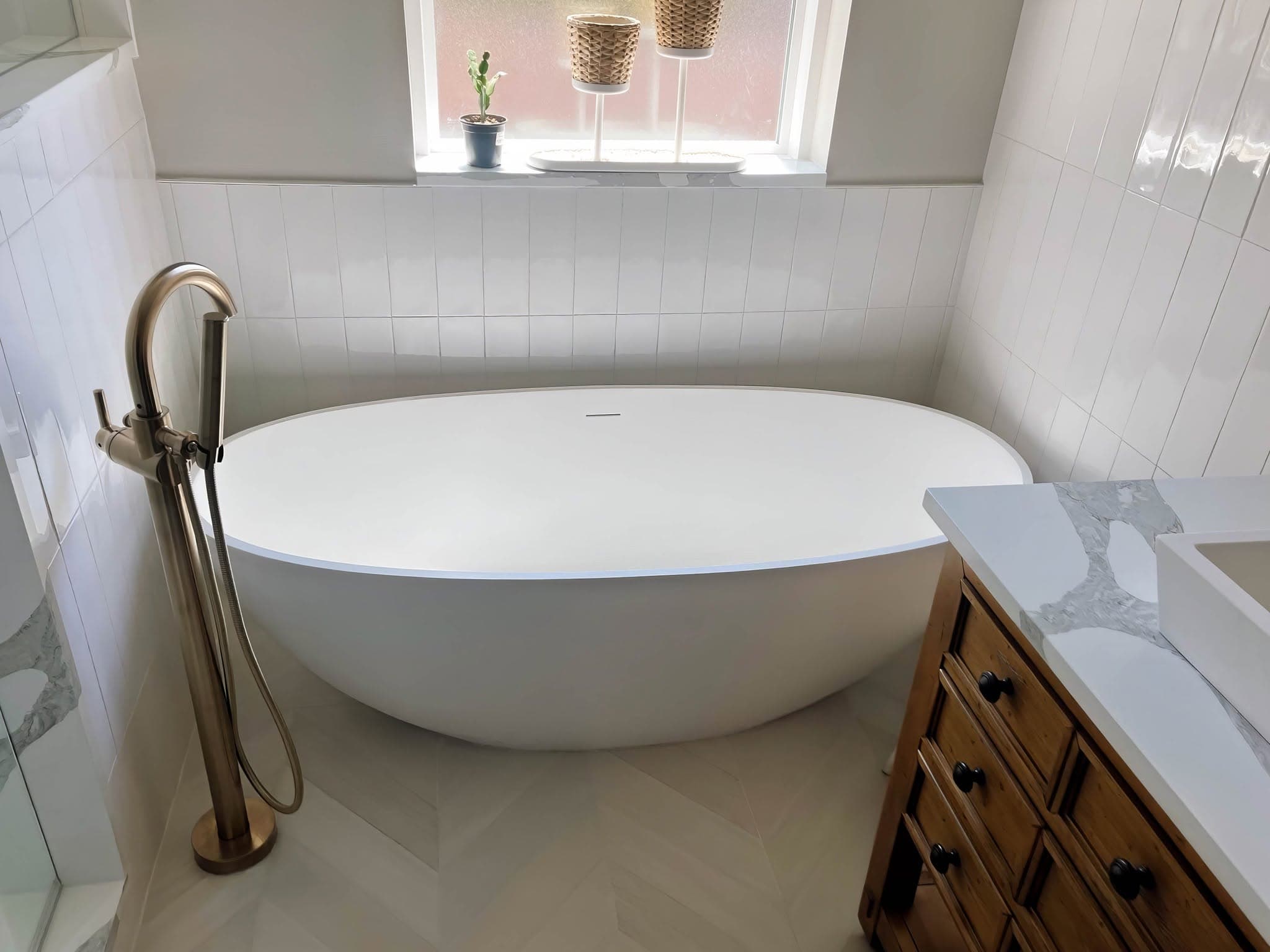 Freestanding soaking tub against a vertical stacked tile surround with large-format tile flooring in a Puget Sound bathroom