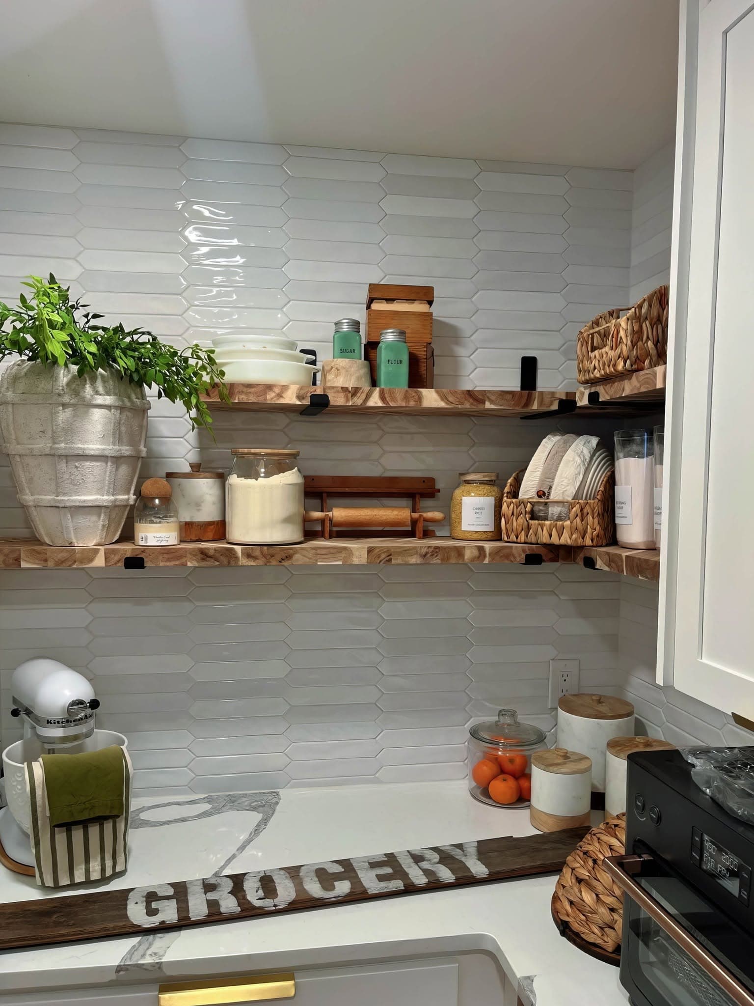 Kitchen backsplash installation using elongated picket tile behind open wood shelving