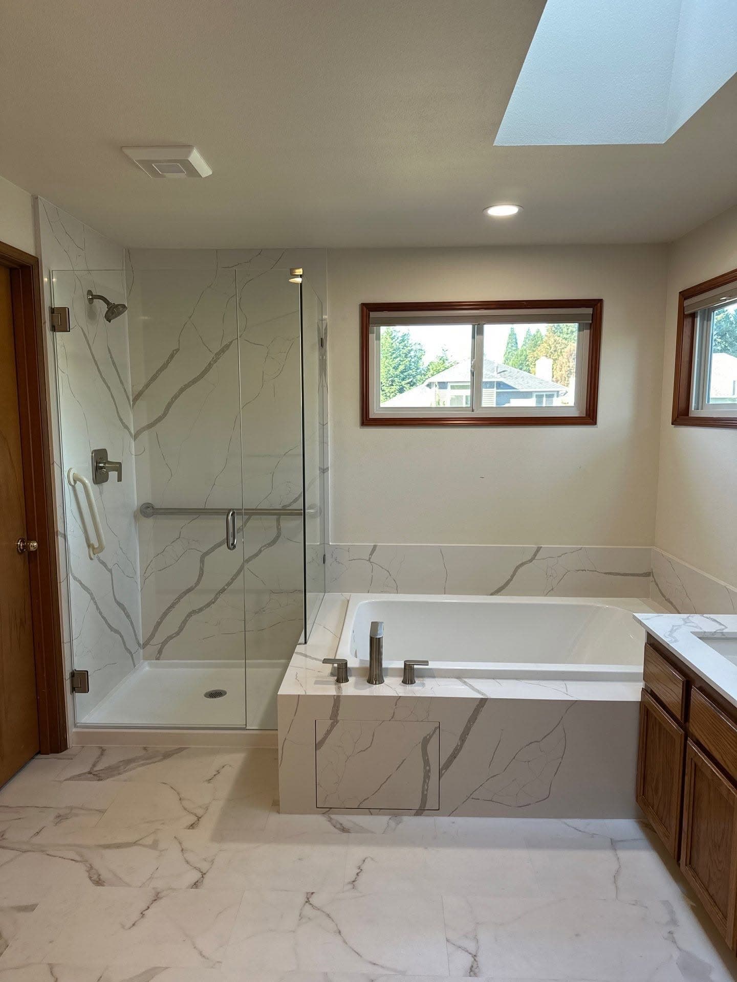 Large-format tile installation across a bathroom floor, shower surround and tub deck
